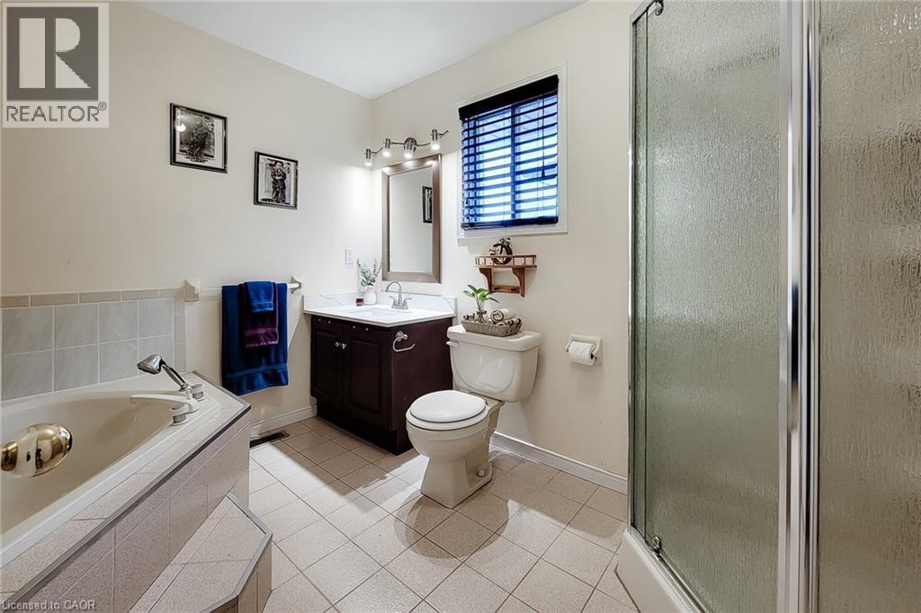 Bathroom featuring a built-in corner tub with tiled surround, a separate glass-enclosed shower, and tile flooring - 146 Locheed Drive, Hamilton, ON - Indoor Photo Showing Bathroom
