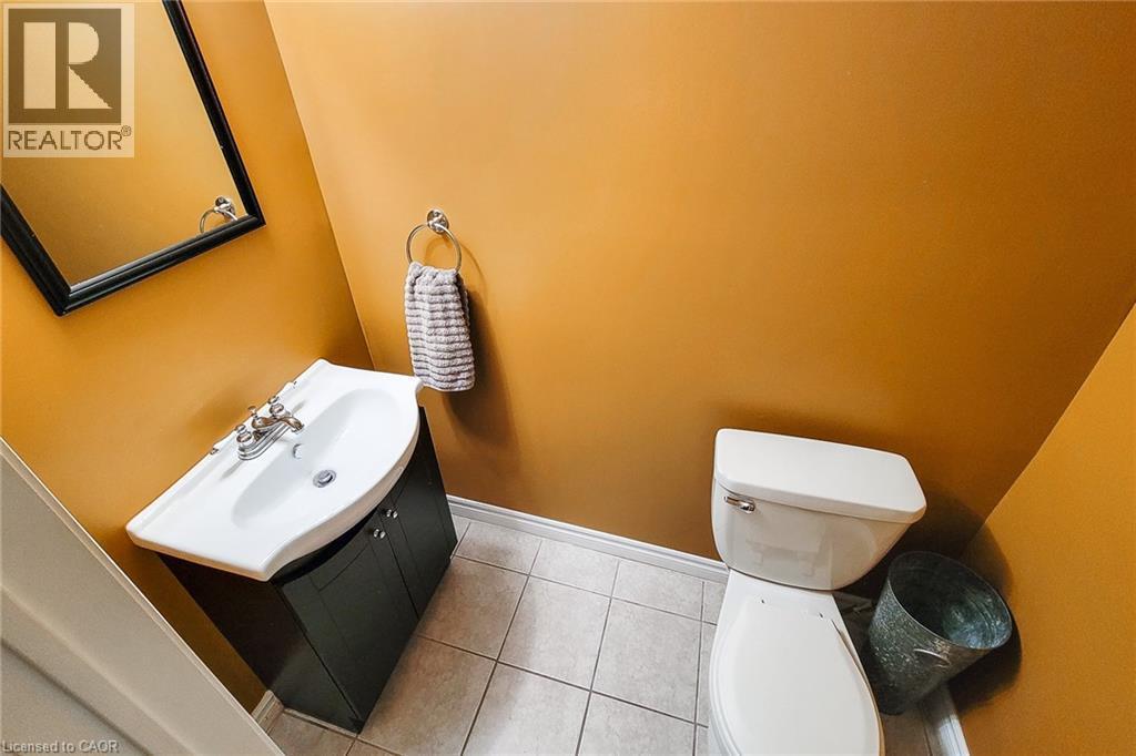 Powder room featuring a white pedestal sink with dark wood-finish vanity, a framed mirror, and tile flooring - 146 Locheed Drive, Hamilton, ON - Indoor Photo Showing Bathroom