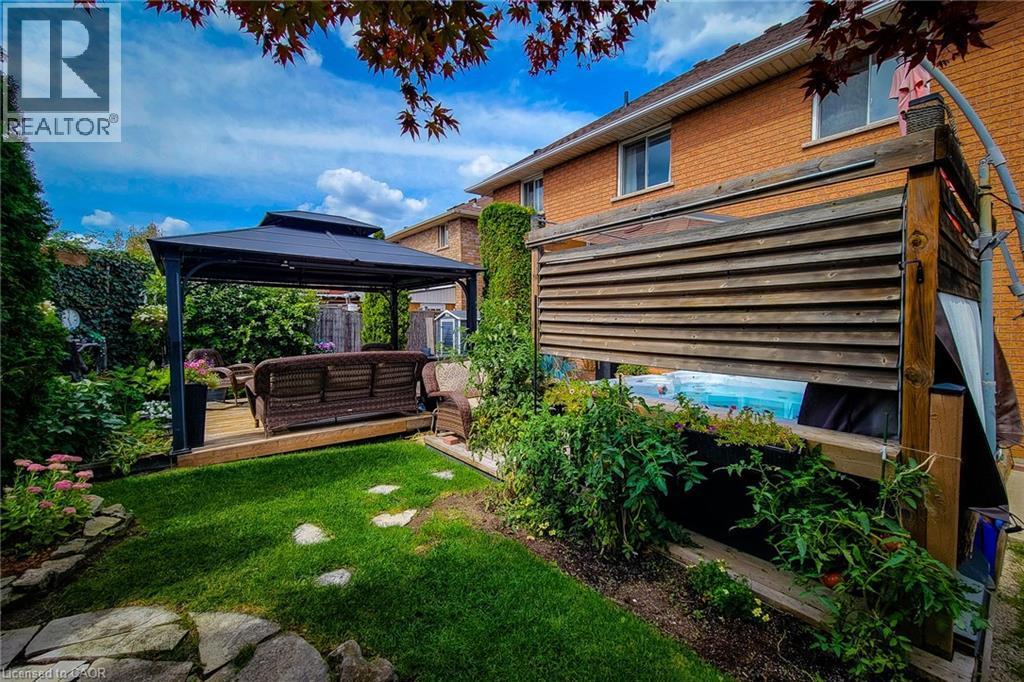Expansive backyard with a manicured lawn, stone pathway, and mature plantings - 146 Locheed Drive, Hamilton, ON - Outdoor With Deck Patio Veranda