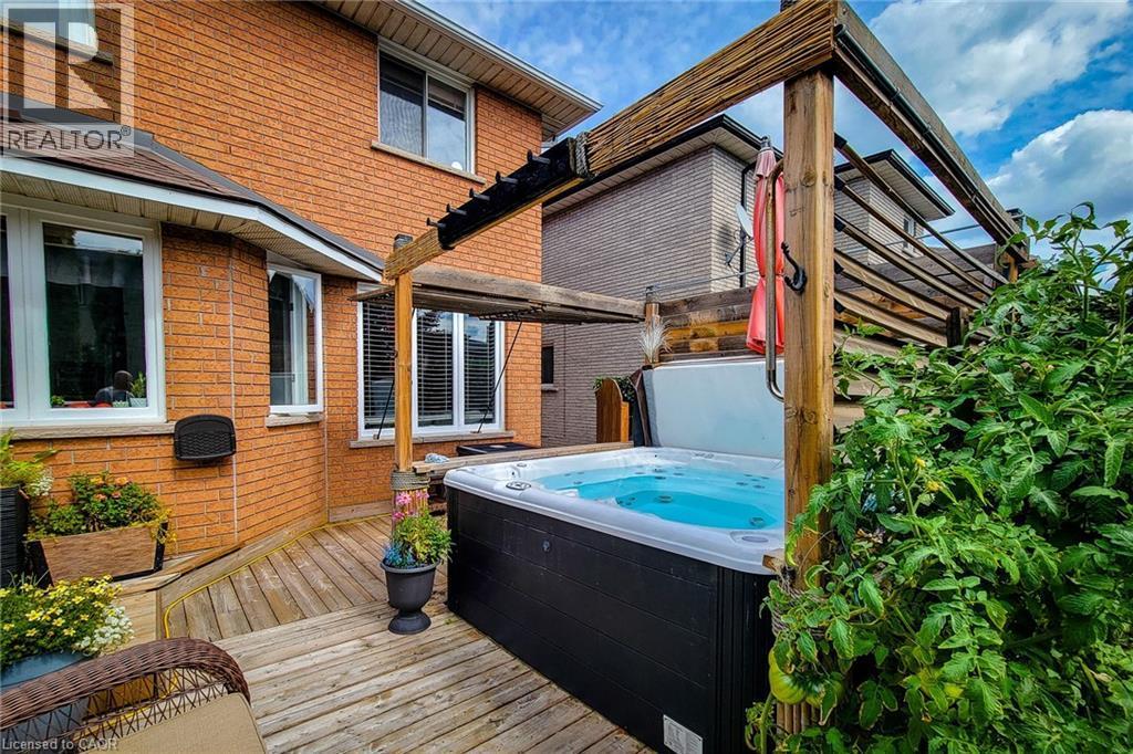 Spacious outdoor deck featuring a built-in hot tub, a pergola structure, and a vibrant green shrub border - 146 Locheed Drive, Hamilton, ON - Outdoor With Deck Patio Veranda With Exterior
