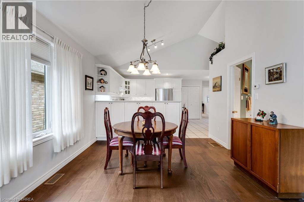 Vaulted ceiling dining area featuring wood-finish flooring, a contemporary chandelier, and a built-in wall niche - 422 Powerline Road Unit# 10, Brantford, ON - Indoor Photo Showing Dining Room