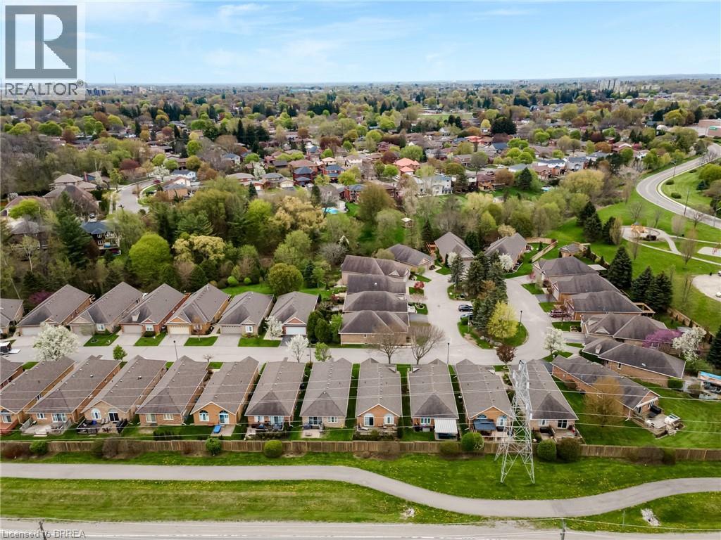 Aerial perspective showcasing residential properties with light-toned brick and siding exteriors, dark shingled roofs, and attached garages - 422 Powerline Road Unit# 10, Brantford, ON - Outdoor With View