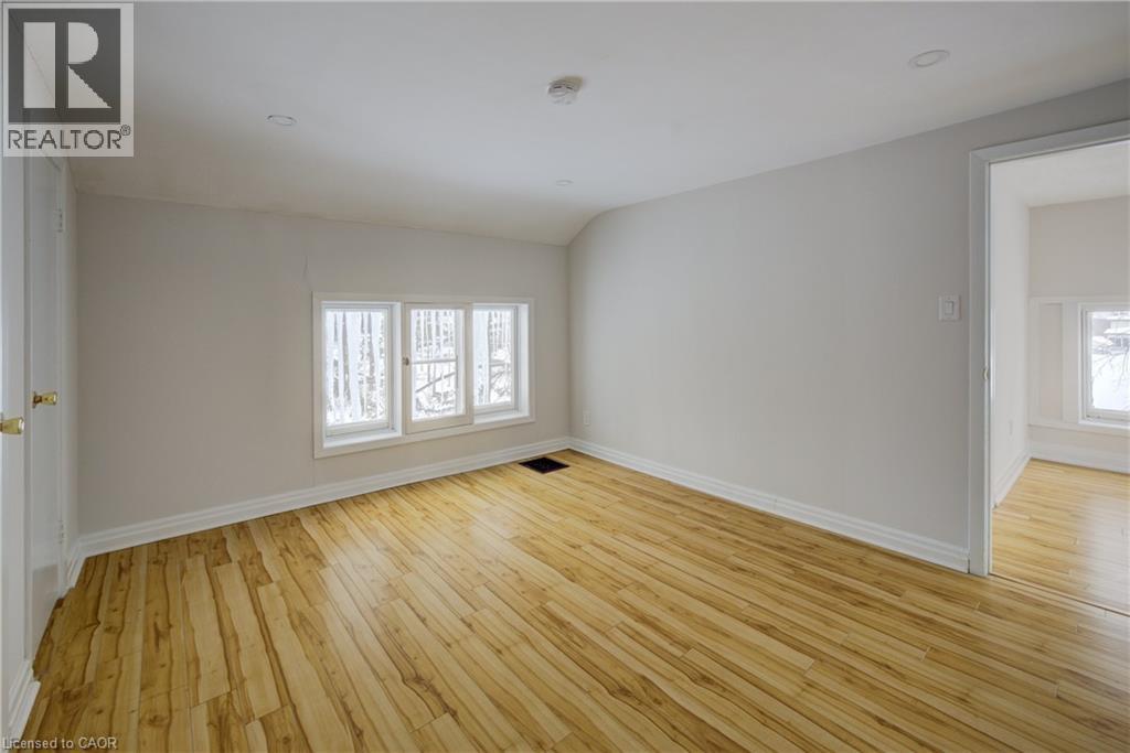 Spacious room featuring light wood-finish flooring, white baseboards, and a triple window unit - 3355 King Street E, Kitchener, ON - Indoor Photo Showing Other Room