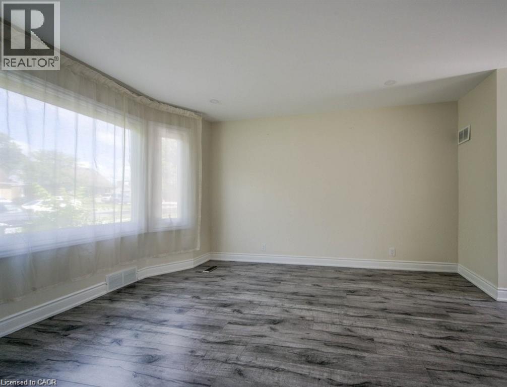 Spacious room featuring wood-finish flooring and a curved bay window - 33 Sixth Avenue, Kitchener, ON - Indoor Photo Showing Other Room