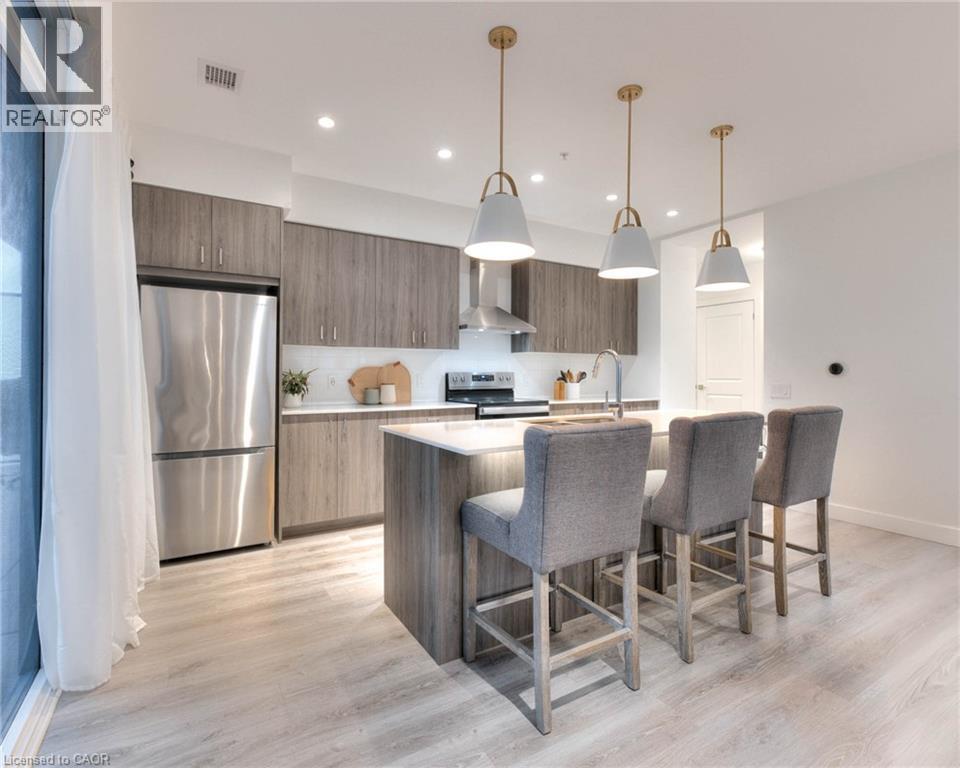 Kitchen featuring stainless steel appliances, modern cabinets, decorative light fixtures, and a center island with sink - 50 Grand Avenue S Unit# 602, Cambridge, ON - Indoor Photo Showing Kitchen With Upgraded Kitchen