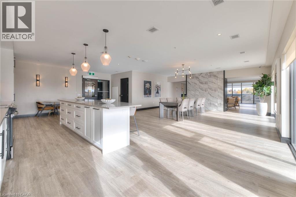 Kitchen featuring open floor plan, white cabinets, a breakfast bar area, hanging light fixtures, and a large island - 50 Grand Avenue S Unit# 602, Cambridge, ON - Indoor