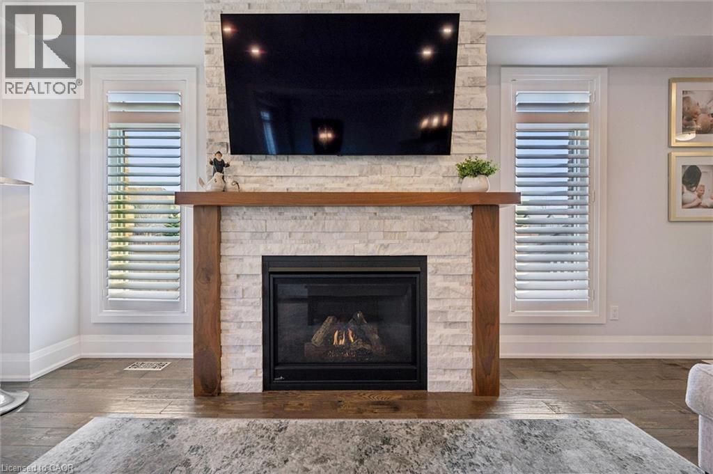 Stone veneer fireplace with wood-finish mantel and integrated gas insert - 72 Elmbank Trail, Kitchener, ON - Indoor Photo Showing Living Room With Fireplace
