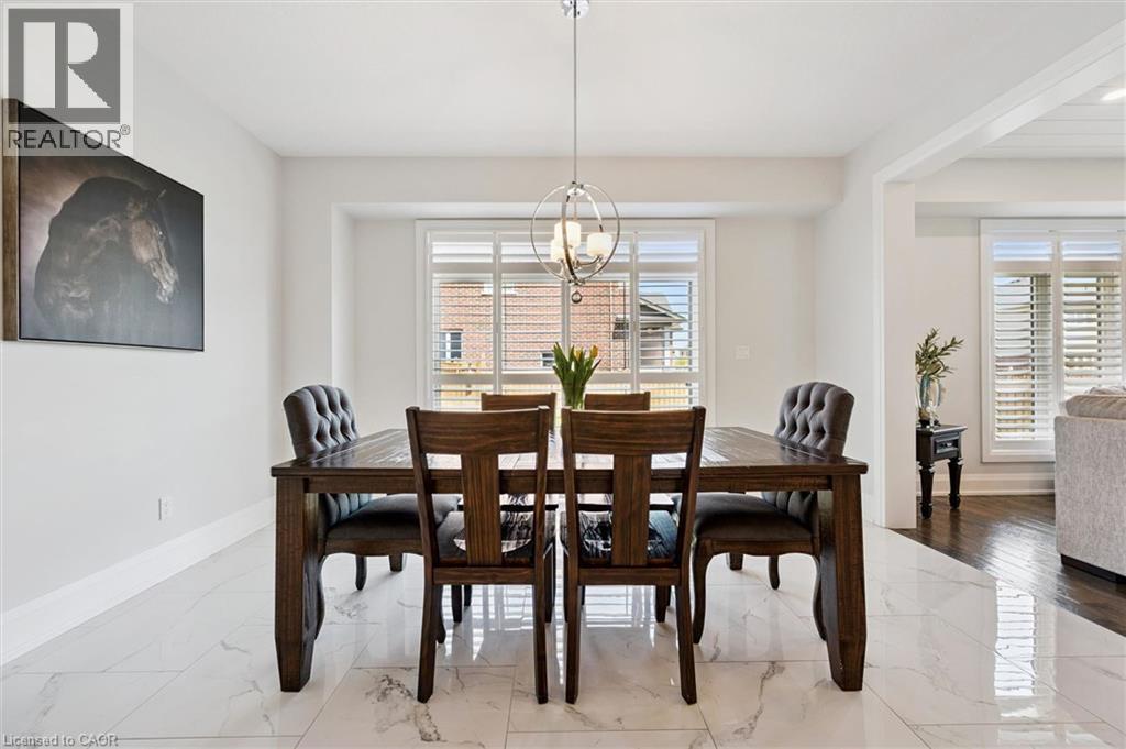 Dining area featuring white marble-look tile flooring, white baseboards, and a contemporary chandelier - 72 Elmbank Trail, Kitchener, ON - Indoor Photo Showing Dining Room