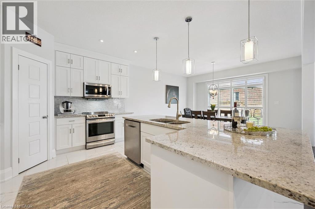 Kitchen featuring a large light-colored countertop island with dual sinks, white cabinetry, stainless steel appliances, and recessed lighting - 72 Elmbank Trail, Kitchener, ON - Indoor Photo Showing Kitchen With Double Sink With Upgraded Kitchen