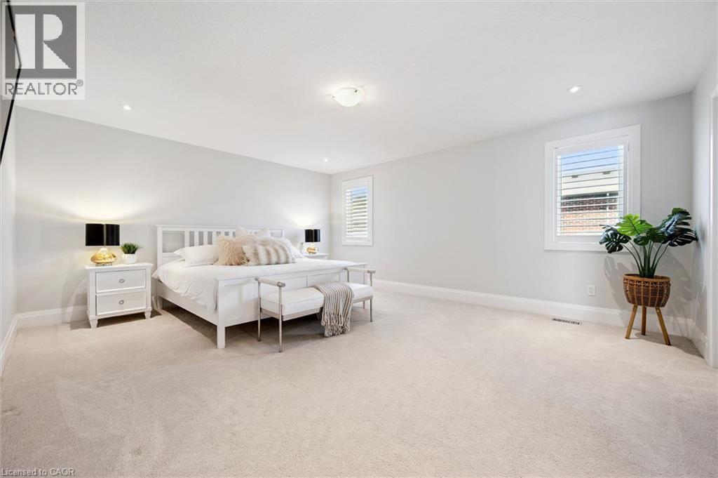 Expansive bedroom featuring light-colored carpeting, two windows with white plantation shutters, and a ceiling light fixture - 72 Elmbank Trail, Kitchener, ON - Indoor Photo Showing Bedroom