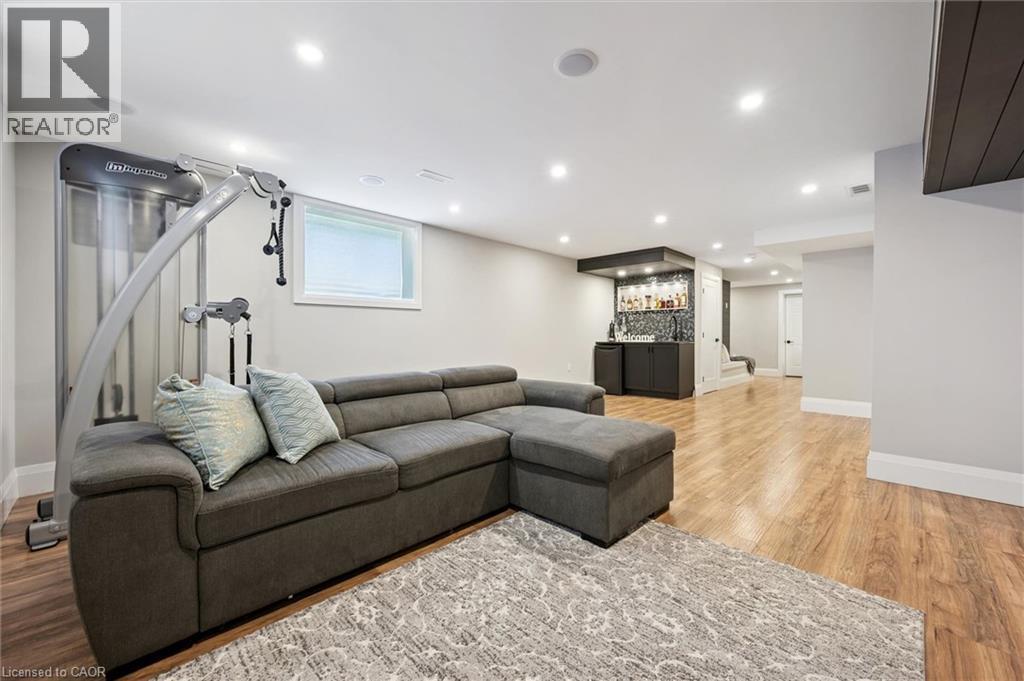 Spacious lower level featuring wood-finish flooring, recessed lighting, and a built-in wet bar with tiled backsplash - 72 Elmbank Trail, Kitchener, ON - Indoor