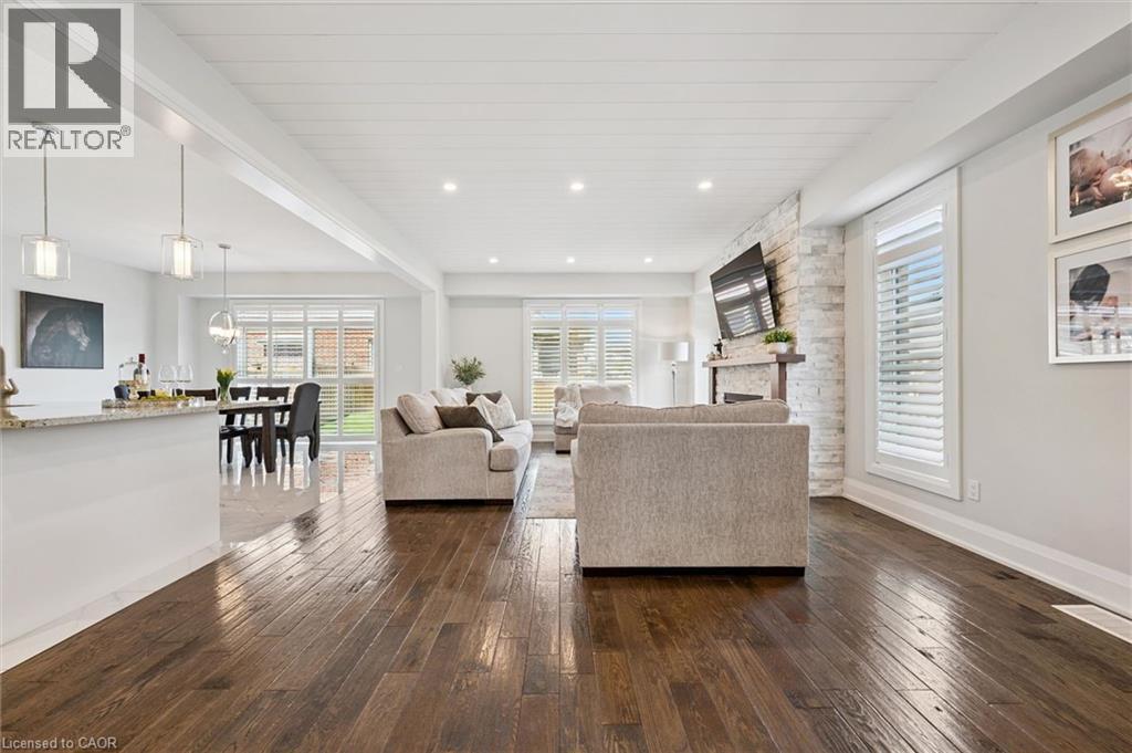 Open-concept living area featuring rich wood-finish flooring, a stone-clad fireplace, and white shiplap ceiling - 72 Elmbank Trail, Kitchener, ON - Indoor Photo Showing Other Room
