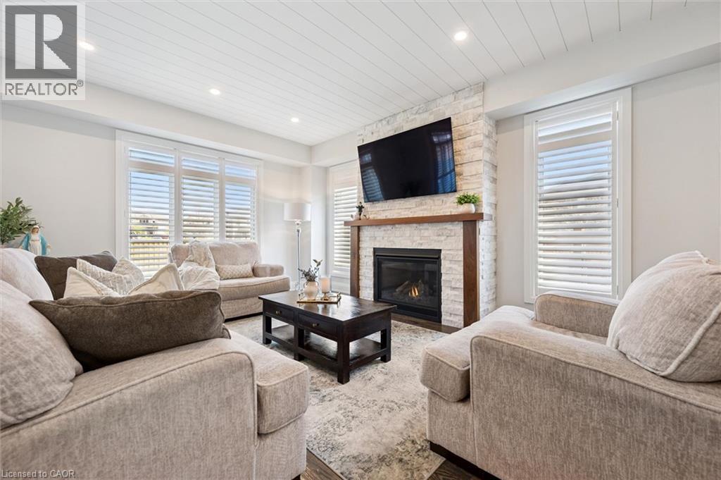 Living area with a stone-clad fireplace featuring a wood mantel - 72 Elmbank Trail, Kitchener, ON - Indoor Photo Showing Living Room With Fireplace