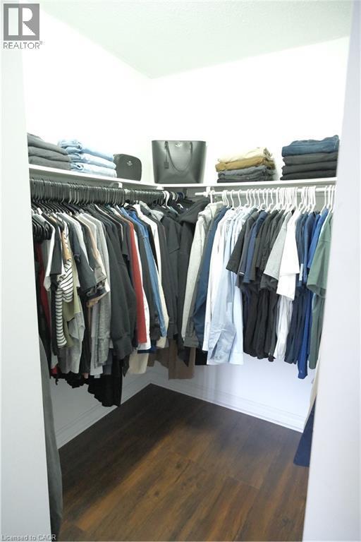 Walk-in closet featuring wood-finish flooring, white baseboards, and built-in shelving with hanging rods - 175 Hunter Street E Unit# 301, Hamilton, ON - Indoor With Storage