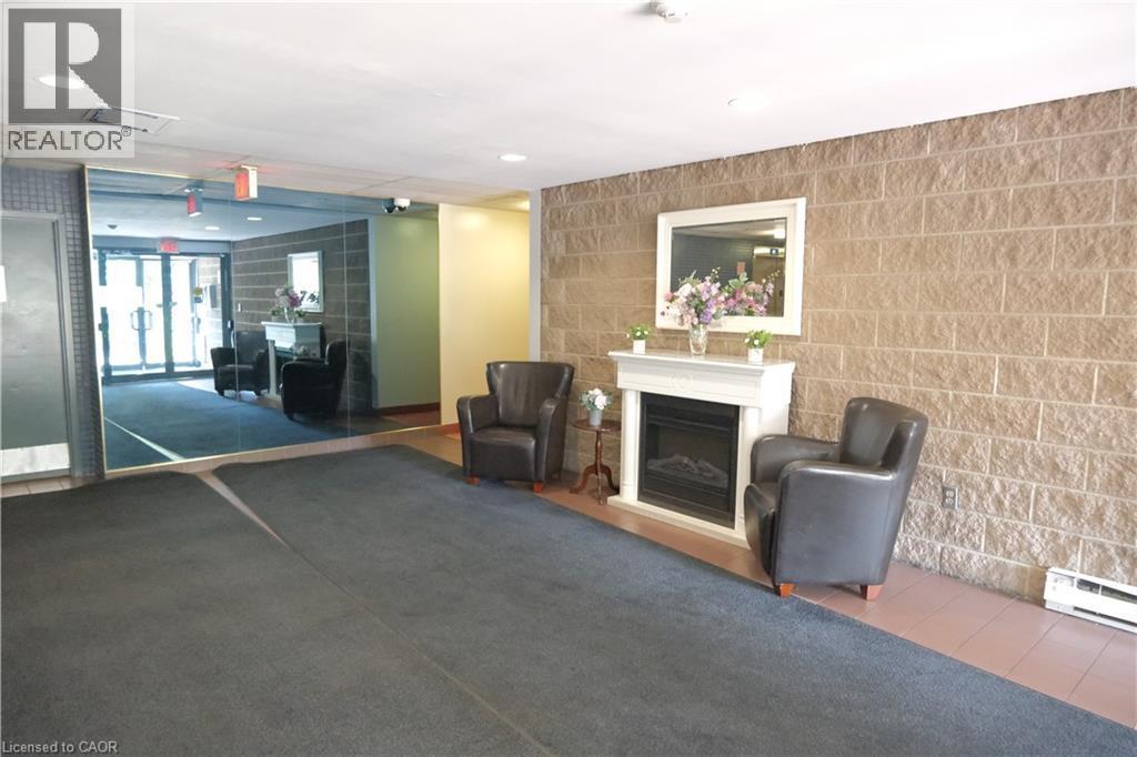 Foyer featuring a white fireplace surround, block wall accents, recessed lighting, and a full-wall mirrored surface - 175 Hunter Street E Unit# 301, Hamilton, ON - Indoor With Fireplace