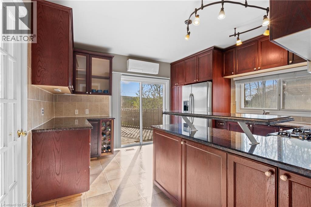 Kitchen featuring dark wood cabinetry, a central island with an integrated breakfast bar, and dark stone countertops - 204 Beach Boulevard, Hamilton, ON - Indoor Photo Showing Kitchen