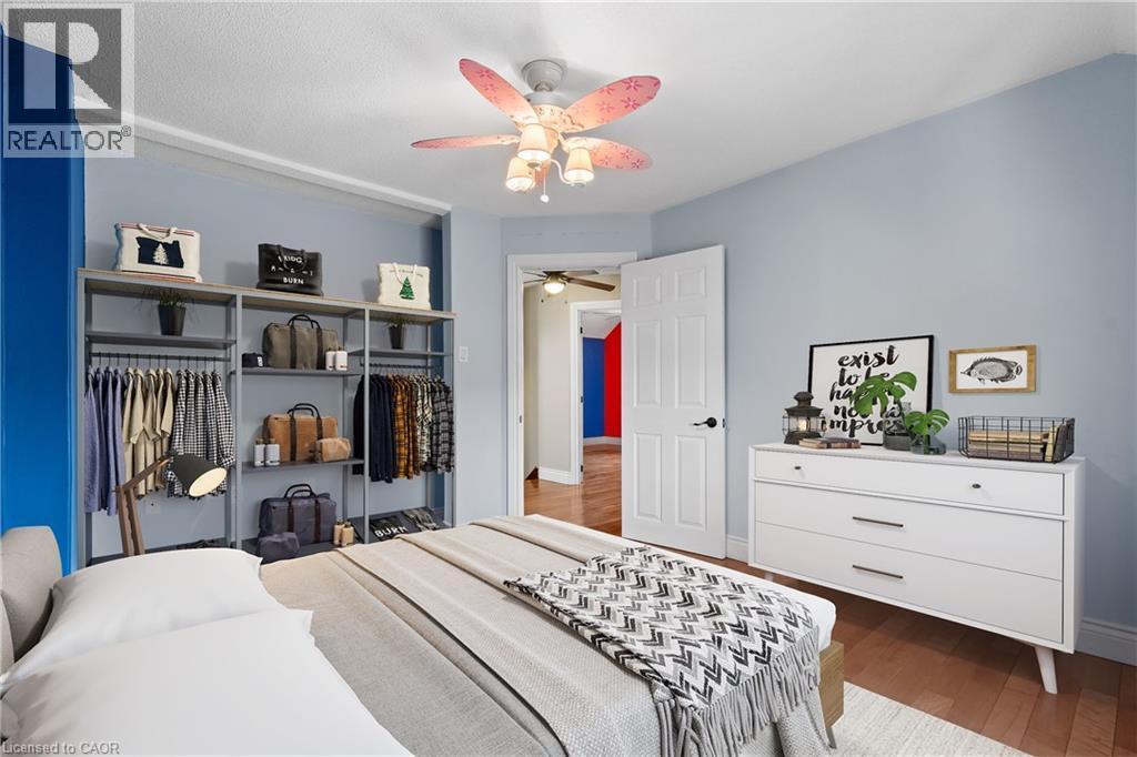Room featuring wood-finish flooring, a ceiling fan with integrated lighting, and a white paneled door with black hardware (Virtually Staged) - 204 Beach Boulevard, Hamilton, ON - Indoor Photo Showing Bedroom