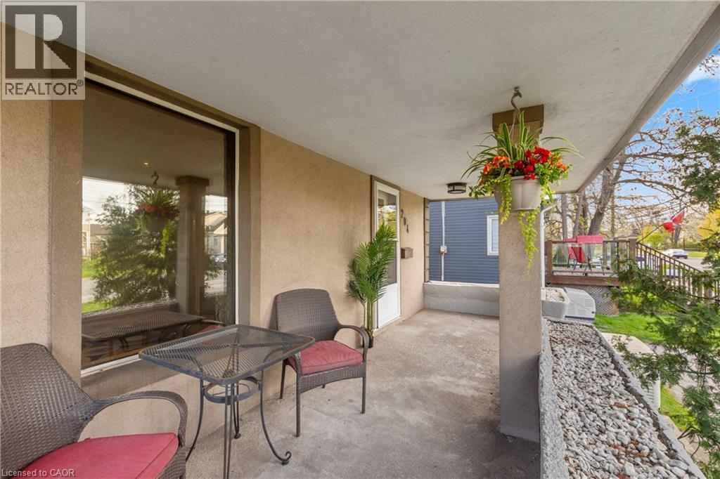Covered porch with concrete flooring, a stucco exterior, and a prominent large window - 204 Beach Boulevard, Hamilton, ON - Outdoor With Exterior