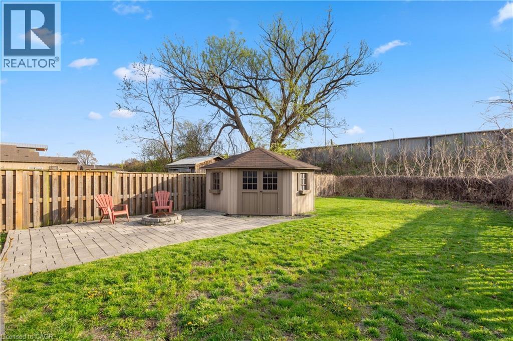 Expansive backyard featuring a central lawn, a distinct paver patio, and a built-in fire pit - 204 Beach Boulevard, Hamilton, ON - Outdoor
