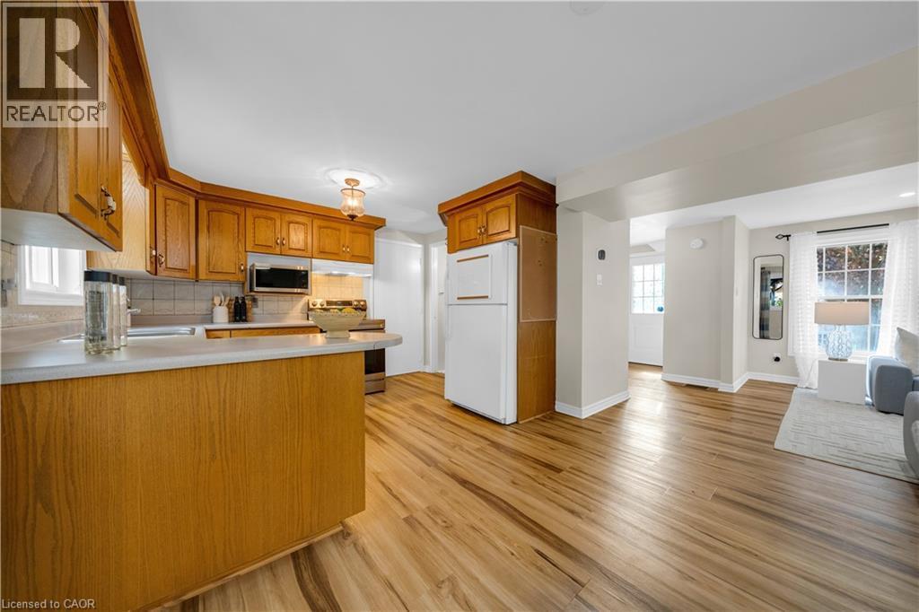 Kitchen featuring wood cabinetry, white countertops, tile backsplash, and stainless steel microwave - 26 Peachtree Crescent, Cambridge, ON - Indoor Photo Showing Kitchen