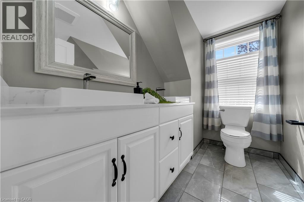 Bathroom featuring a white vanity with black hardware, a rectangular undermount sink, and a large framed mirror - 26 Peachtree Crescent, Cambridge, ON - Indoor Photo Showing Bathroom