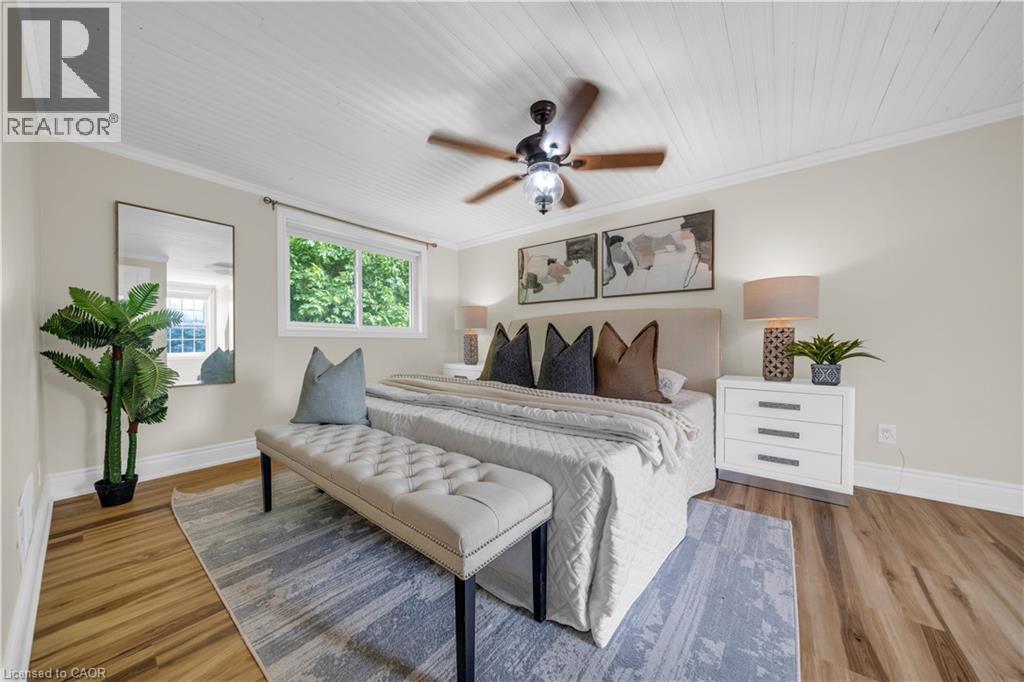 Bedroom featuring wood-finish flooring, a white paneled ceiling, crown molding, a window with exterior foliage visible, and a ceiling fan with integrated lighting - 26 Peachtree Crescent, Cambridge, ON - Indoor Photo Showing Bedroom