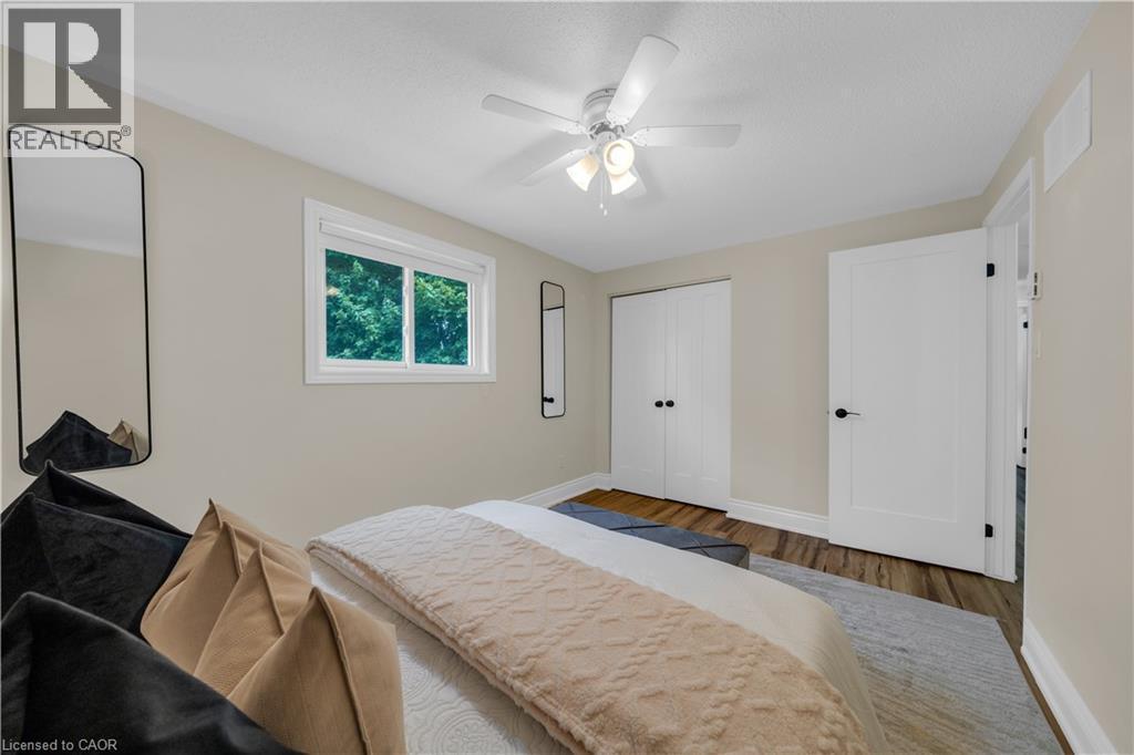Bedroom featuring wood-finish flooring, a contemporary ceiling fan with integrated lighting, a double-panel closet with matte black hardware, and a single window with white trim - 26 Peachtree Crescent, Cambridge, ON - Indoor