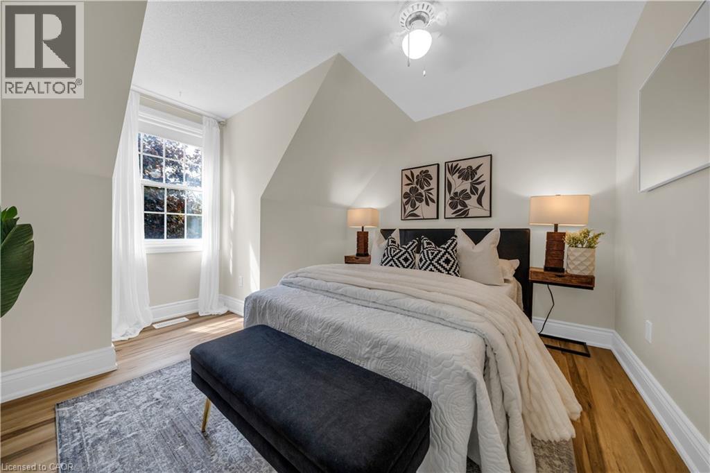 Bedroom featuring a vaulted ceiling with a flush-mount light fixture, wood-finish flooring, a window with white trim, and light-toned walls - 26 Peachtree Crescent, Cambridge, ON - Indoor Photo Showing Bedroom