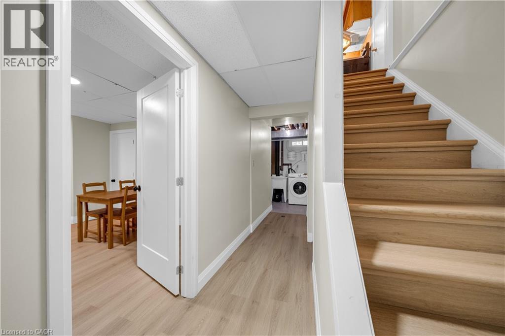 Wood-finish flooring throughout the hallway and room, complemented by a white paneled door - 26 Peachtree Crescent, Cambridge, ON - Indoor Photo Showing Other Room