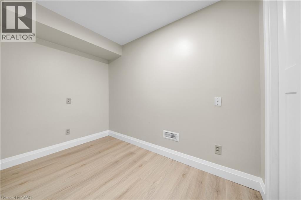 Neutral-toned room featuring light wood-finish flooring, white baseboards, and a contemporary white interior door with panel detailing - 26 Peachtree Crescent, Cambridge, ON - Indoor Photo Showing Other Room