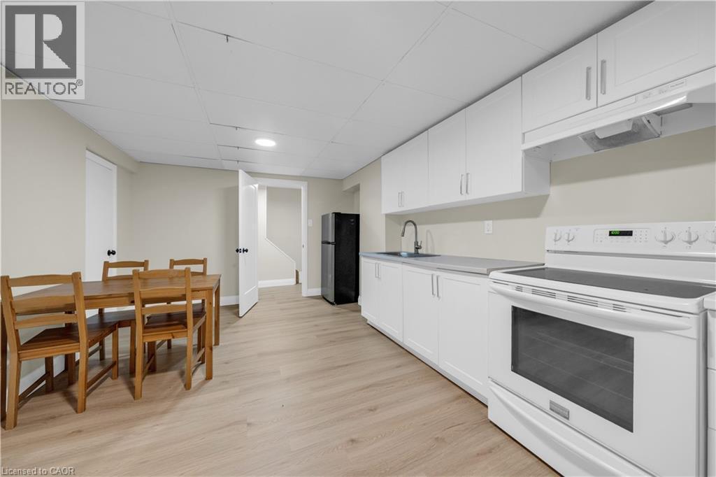 Kitchen area featuring a white electric range, black refrigerator, and a stainless steel sink - 26 Peachtree Crescent, Cambridge, ON - Indoor