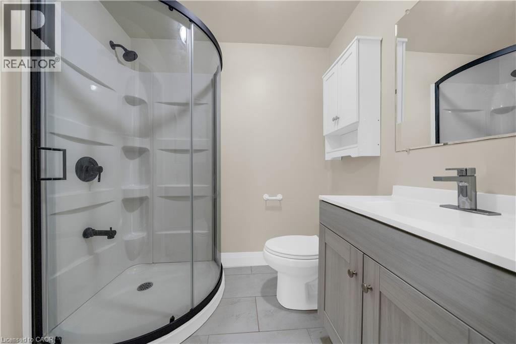 Bathroom featuring a curved glass shower enclosure with black trim, a gray wood-finish vanity with a white countertop, and a coordinating wall-mounted storage cabinet - 26 Peachtree Crescent, Cambridge, ON - Indoor Photo Showing Bathroom
