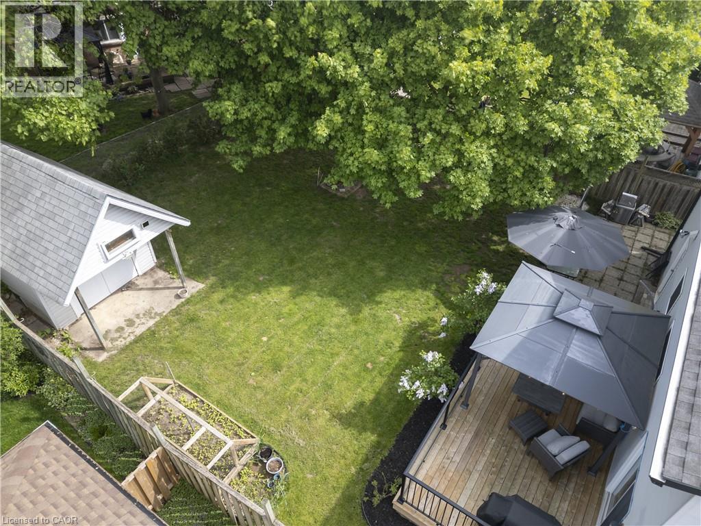 Expansive backyard featuring a spacious wood deck, privacy fencing, detached storage shed, and mature trees - 26 Peachtree Crescent, Cambridge, ON - Outdoor