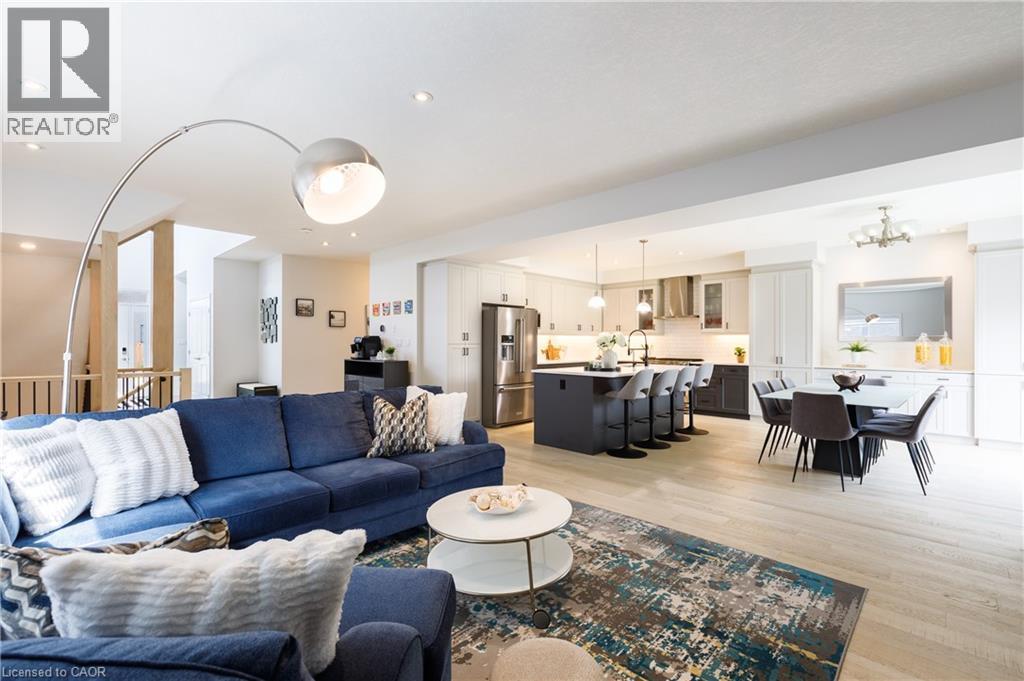 Open-concept living area featuring light wood-finish flooring, recessed lighting, a modern kitchen with a central island, stainless steel appliances, and an integrated dining area - 581 Doonwoods Crescent, Kitchener, ON - Indoor Photo Showing Living Room
