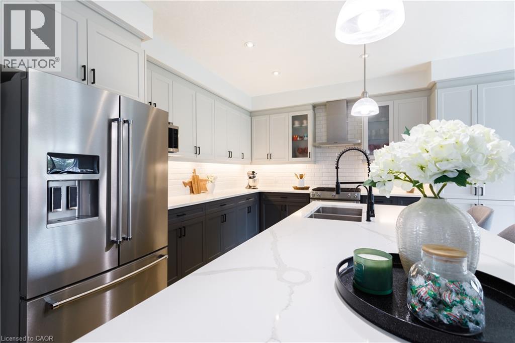 Contemporary kitchen featuring a large white countertop island, stainless steel appliances, two-tone cabinetry, subway tile backsplash, and recessed lighting - 581 Doonwoods Crescent, Kitchener, ON - Indoor Photo Showing Kitchen With Stainless Steel Kitchen With Double Sink With Upgraded Kitchen