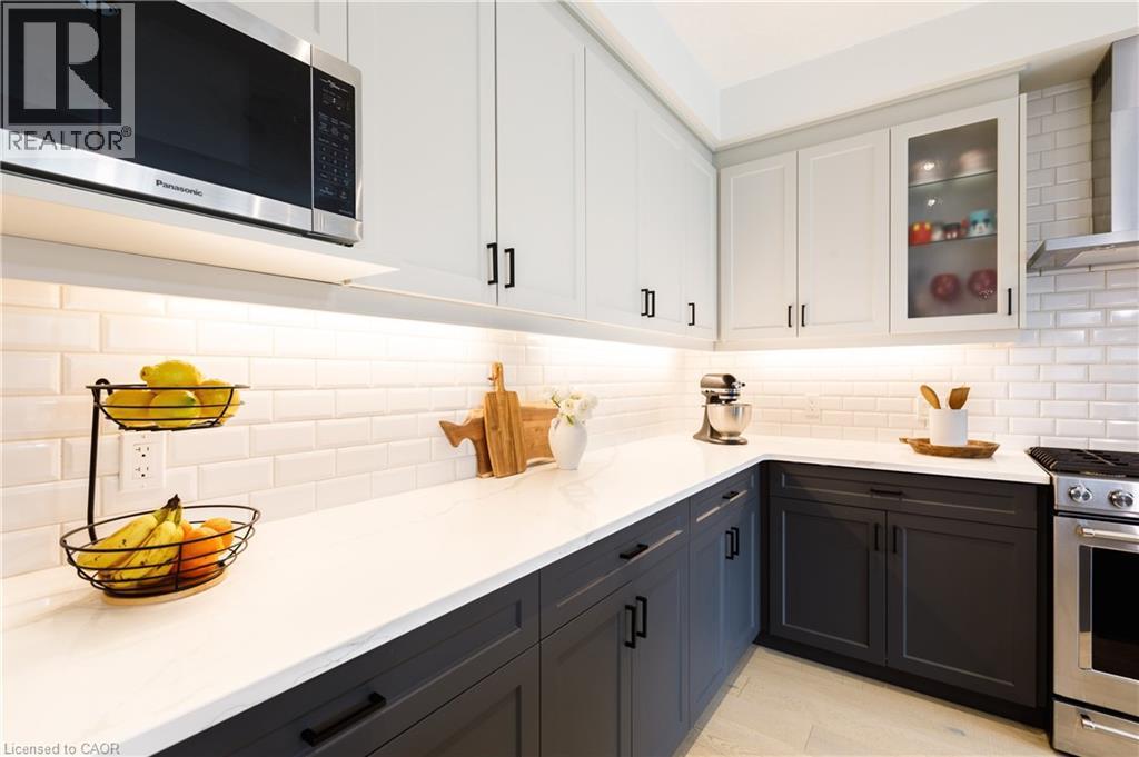Contemporary kitchen featuring two-tone cabinetry with matte black hardware, white subway tile backsplash, and under-cabinet lighting - 581 Doonwoods Crescent, Kitchener, ON - Indoor Photo Showing Kitchen