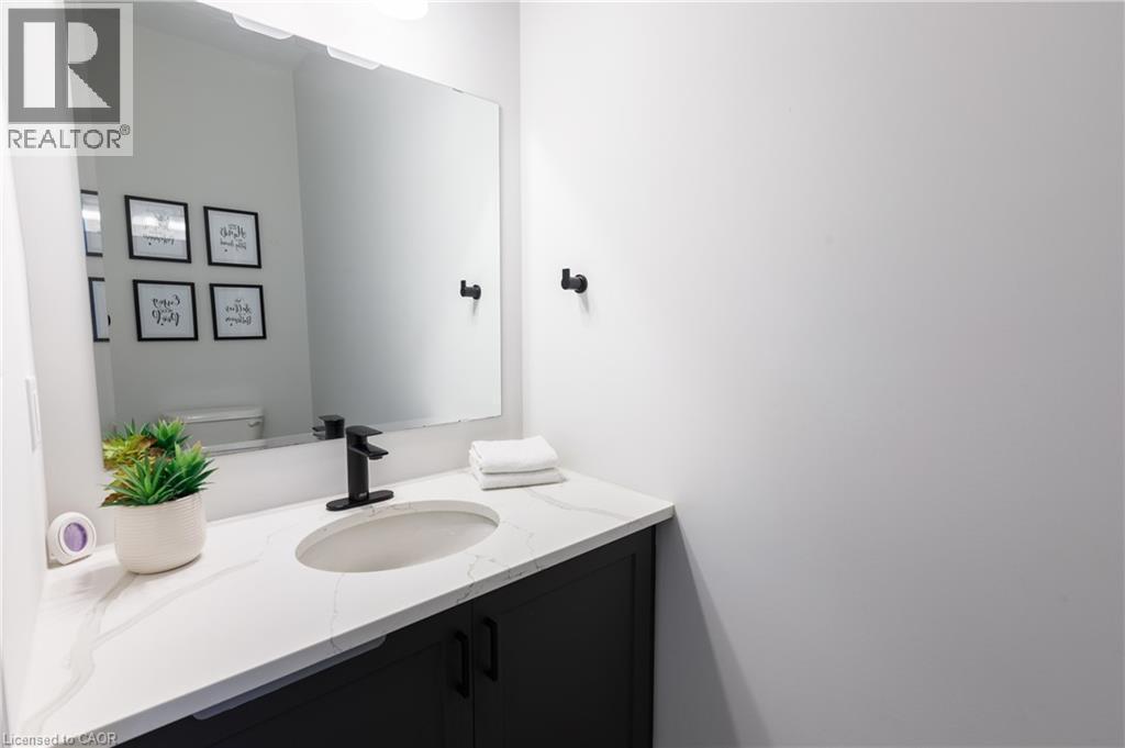 Bathroom vanity featuring a rectangular sink set into a white countertop, matte black faucet, and dark cabinetry - 581 Doonwoods Crescent, Kitchener, ON - Indoor Photo Showing Bathroom