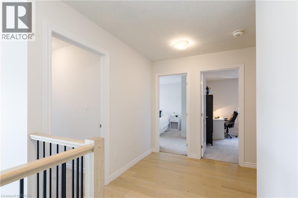 Second-story hallway featuring light wood-finish flooring, white walls, white trim, and a contemporary flush-mount ceiling light - 581 Doonwoods Crescent, Kitchener, ON - Indoor