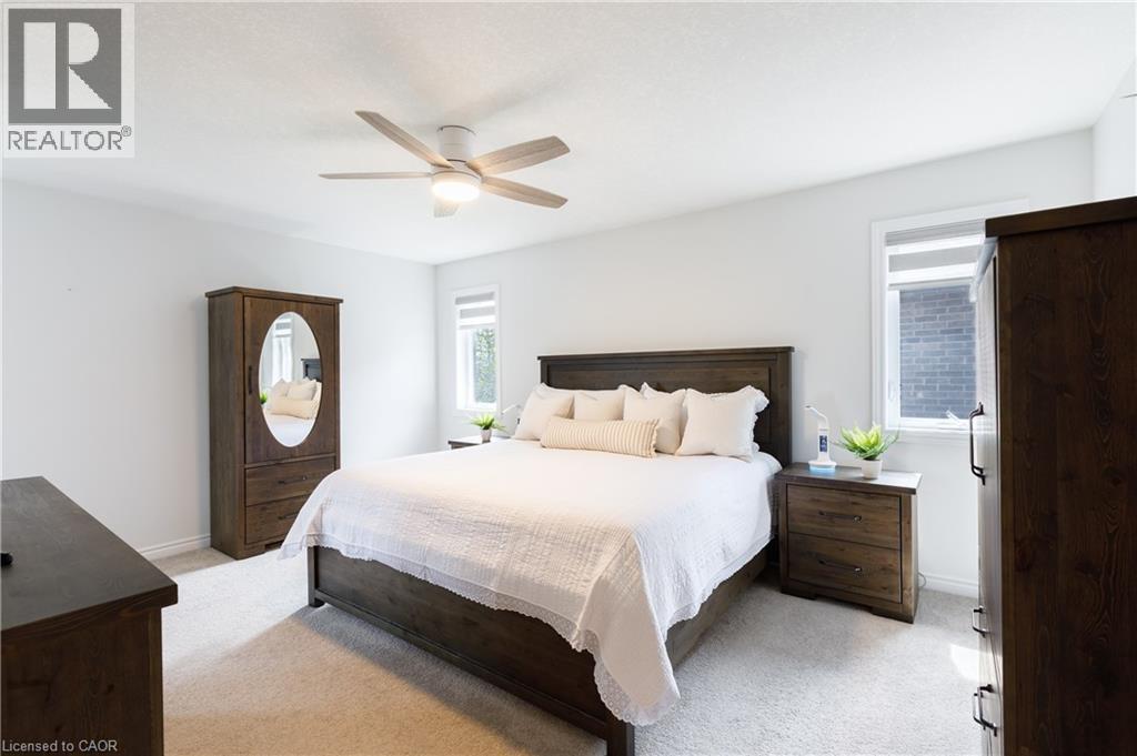 Carpeted bedroom featuring a ceiling fan with integrated lighting, multiple windows with roller blinds, and light neutral wall colors - 581 Doonwoods Crescent, Kitchener, ON - Indoor Photo Showing Bedroom