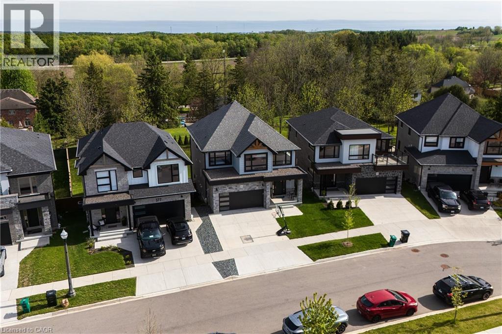 Contemporary residential street featuring multiple homes with dark shingle roofs - 581 Doonwoods Crescent, Kitchener, ON - Outdoor With Facade