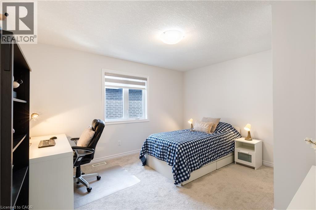 Light-filled room featuring neutral wall tones, textured carpeting, a window with horizontal blinds, and a ceiling-mounted light fixture - 581 Doonwoods Crescent, Kitchener, ON - Indoor Photo Showing Bedroom