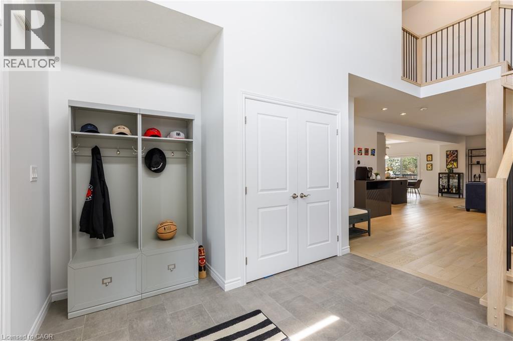 Entryway featuring light gray tile flooring, a built-in storage unit, double panel doors, and a wood-finish staircase with black balusters - 581 Doonwoods Crescent, Kitchener, ON - Indoor Photo Showing Other Room