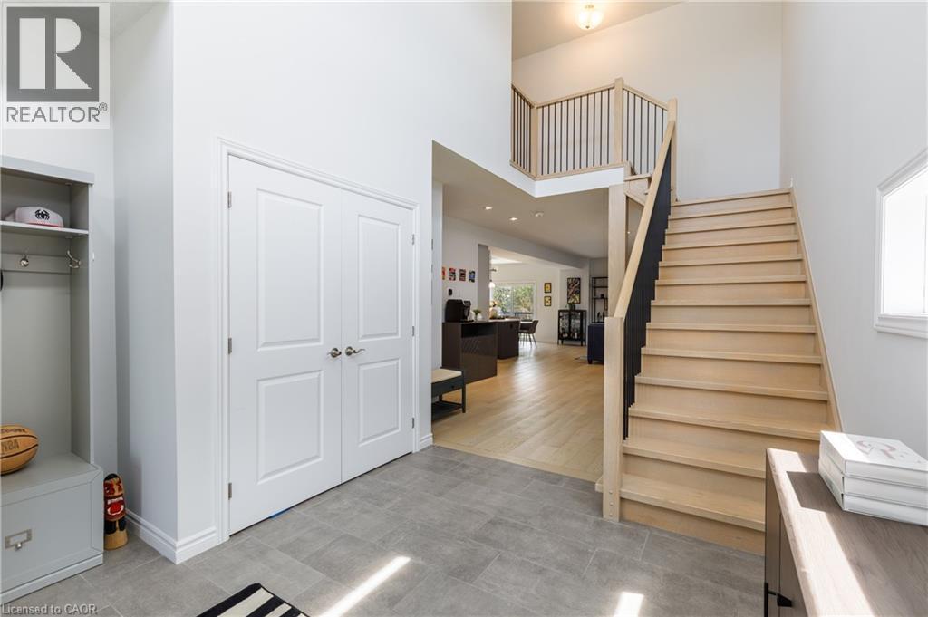 Foyer featuring light wood-finish flooring, a two-story ceiling, a staircase with black metal balusters, double panel doors, and tile flooring - 581 Doonwoods Crescent, Kitchener, ON - Indoor Photo Showing Other Room