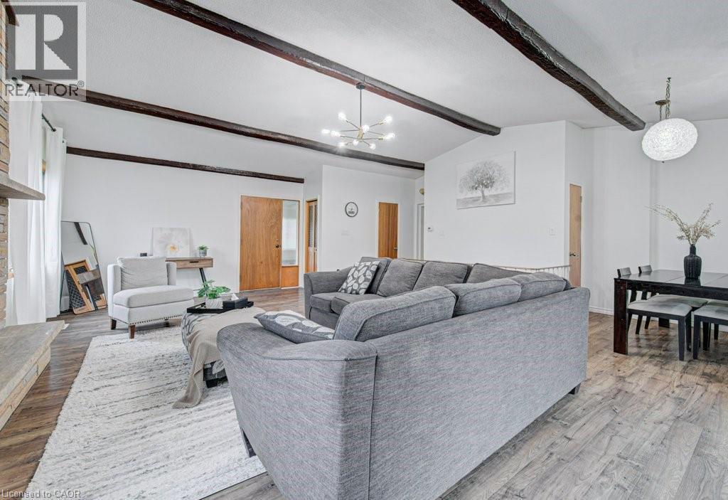 Open concept living space featuring wood-finish flooring, exposed ceiling beams, a stone fireplace, and light wood interior doors - 128 Pollock Avenue, Cambridge, ON - Indoor Photo Showing Living Room