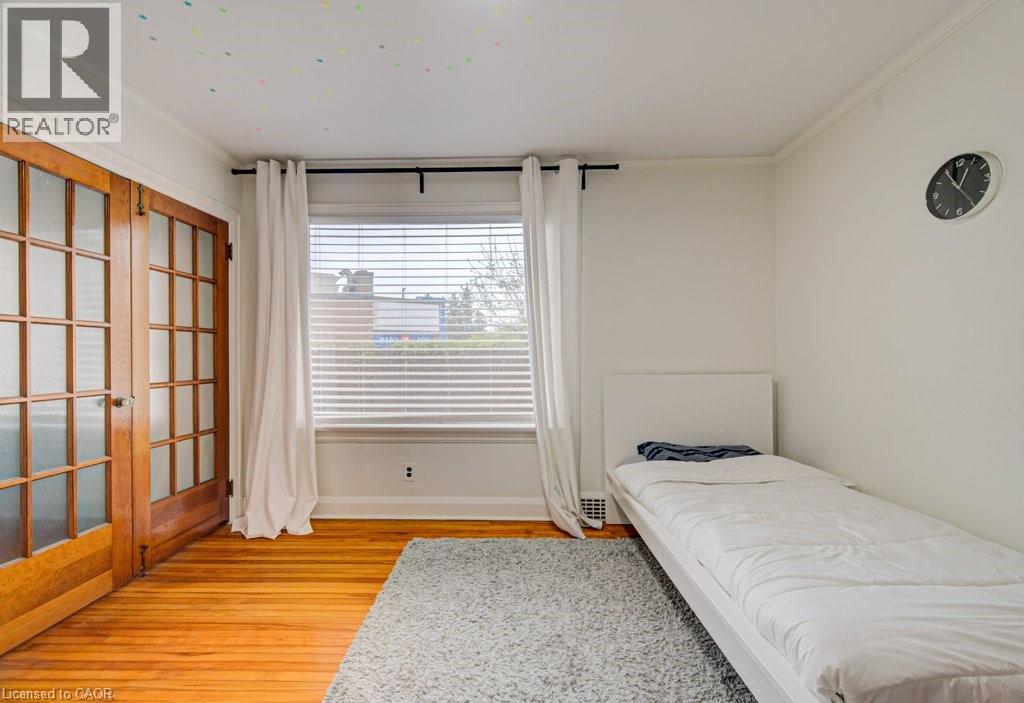 Bright interior space featuring wood-finish flooring, white walls, and crown molding - 128 Pollock Avenue, Cambridge, ON - Indoor Photo Showing Bedroom