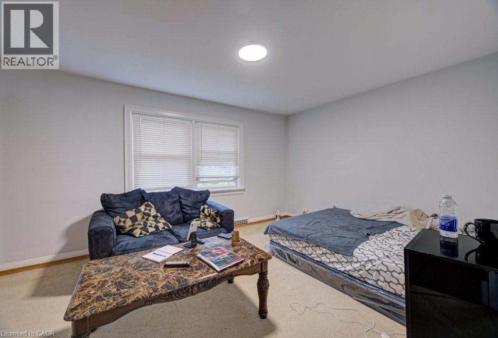 Carpeted room featuring a double window with blinds, white walls, and a ceiling-mounted light fixture - 128 Pollock Avenue, Cambridge, ON - Indoor