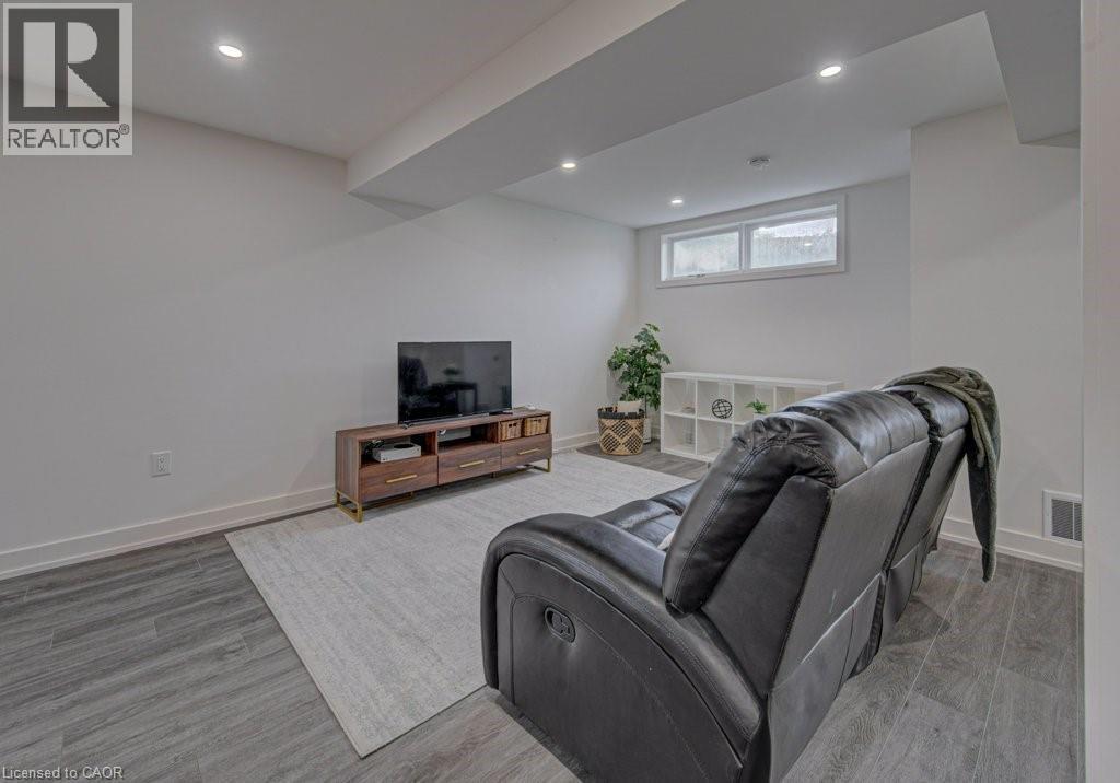 Spacious living area featuring wood-finish flooring, recessed lighting, and a white baseboard trim - 128 Pollock Avenue, Cambridge, ON - Indoor