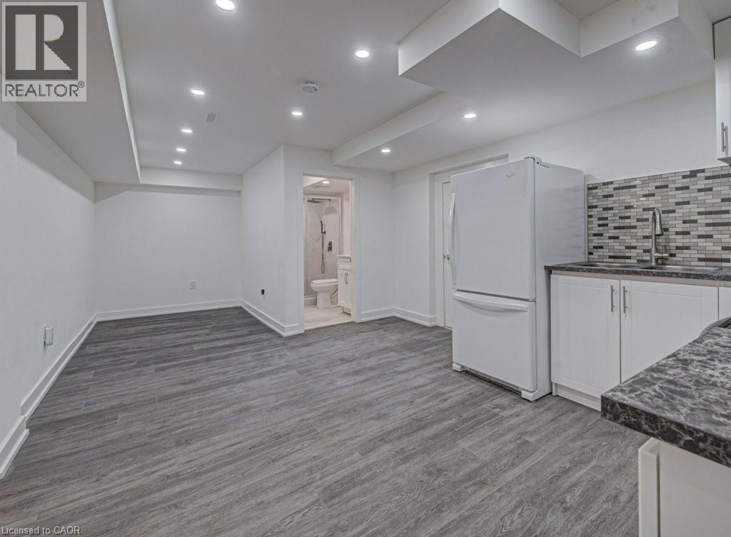 Open-concept living space featuring wood-finish flooring, recessed lighting, and a white appliance package - 128 Pollock Avenue, Cambridge, ON - Indoor