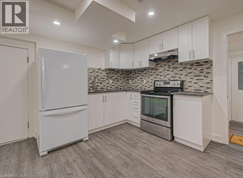 Compact kitchen featuring white cabinetry, a mosaic tile backsplash, stainless steel range, and wood-finish flooring - 128 Pollock Avenue, Cambridge, ON - Indoor Photo Showing Kitchen With Upgraded Kitchen