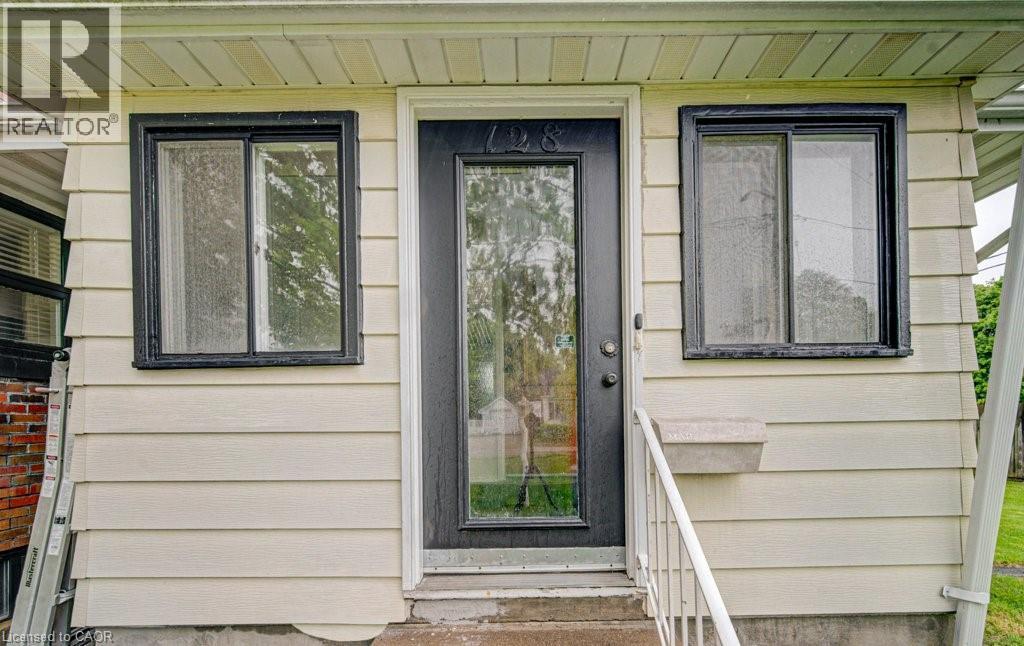 Cream horizontal siding with a black front door featuring a full-light glass insert - 128 Pollock Avenue, Cambridge, ON - Outdoor With Exterior